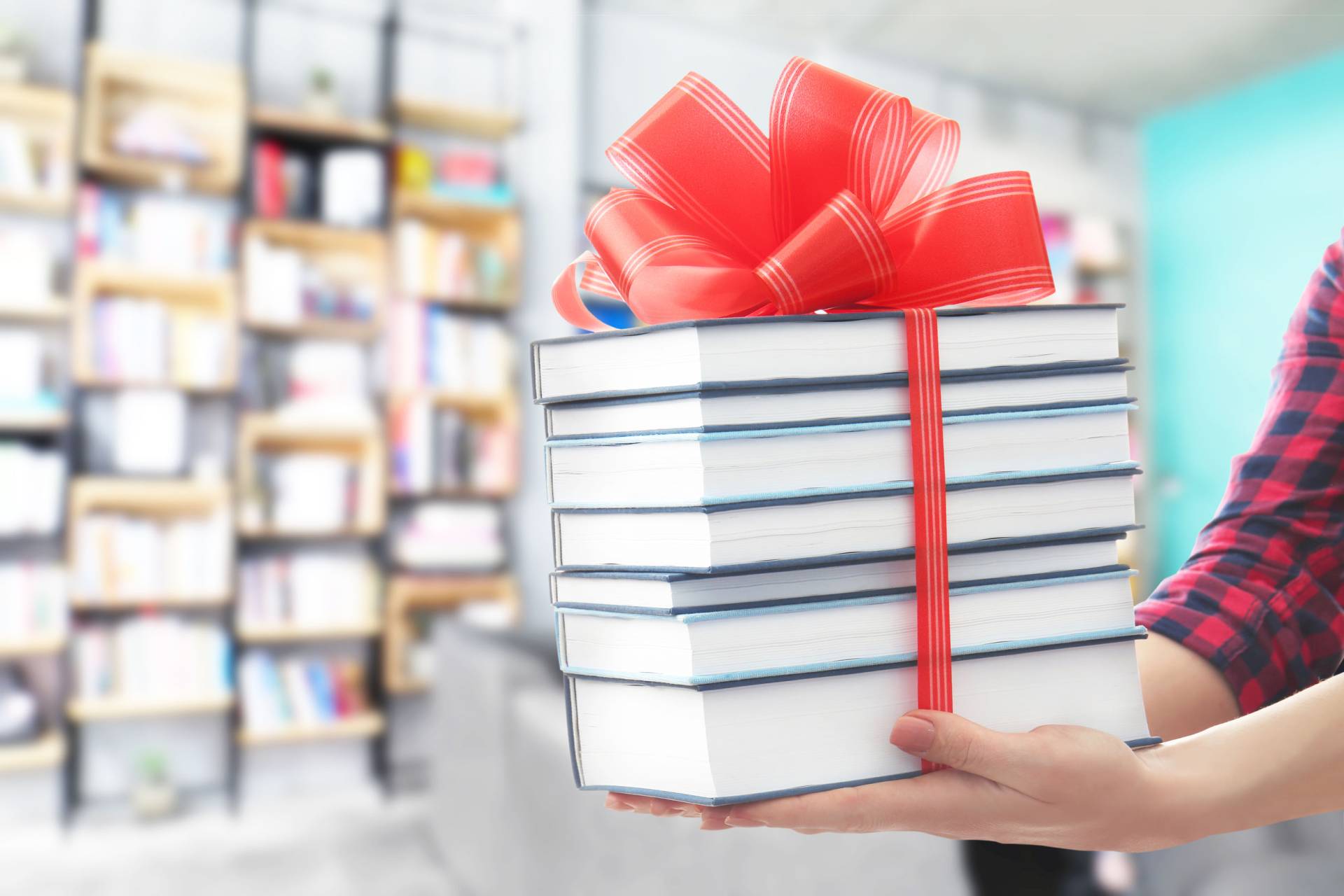 Woman holding books with ribbon bow as gift at library